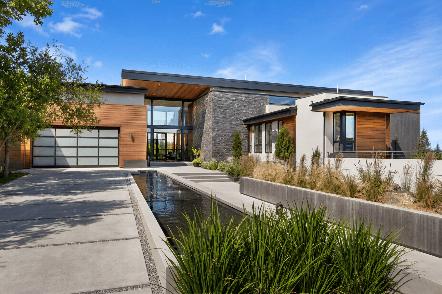 Contemporary luxury custom home with wood cladding, stone, and a water feature